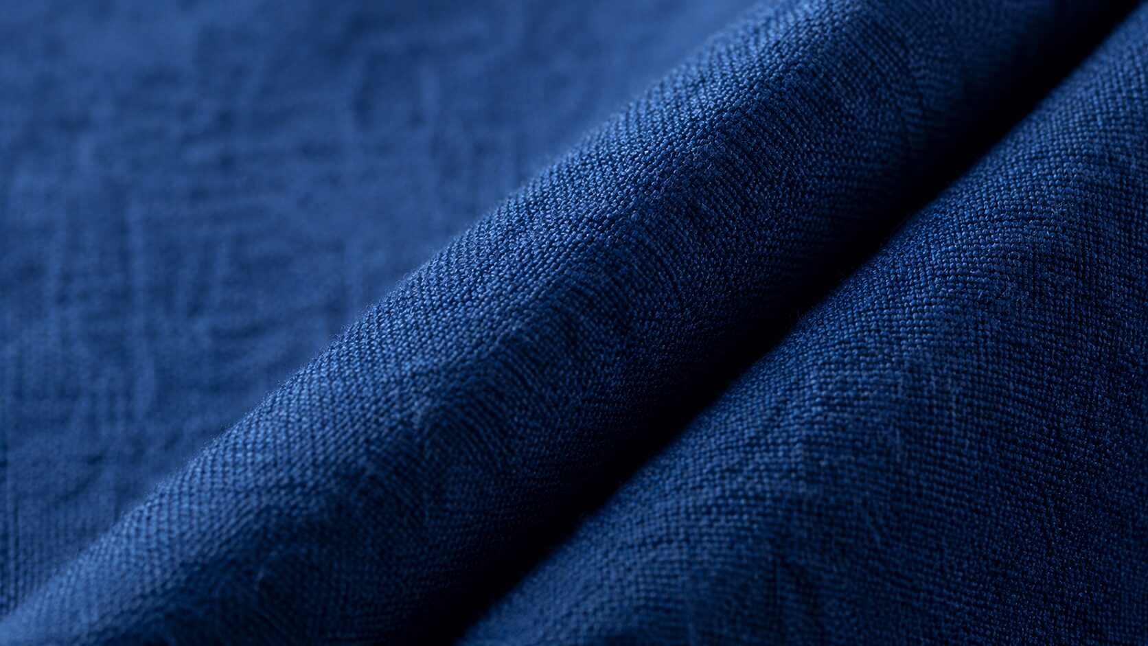 Close-up of indigo-dyed cotton hakama fabric showing the weave texture and a crisp pleat fold
